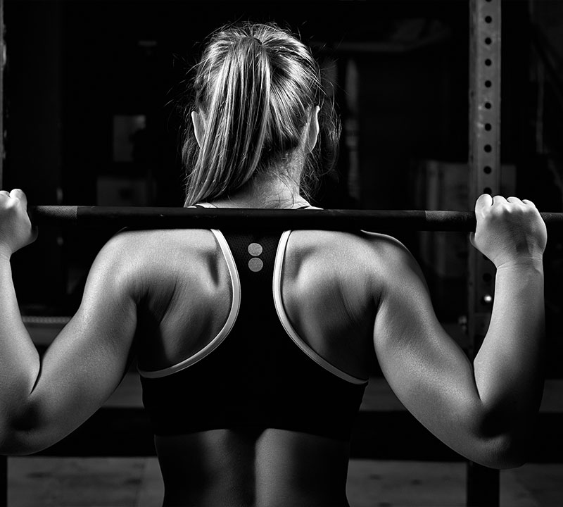 home-hero-1 a woman with a barbell across her shoulders